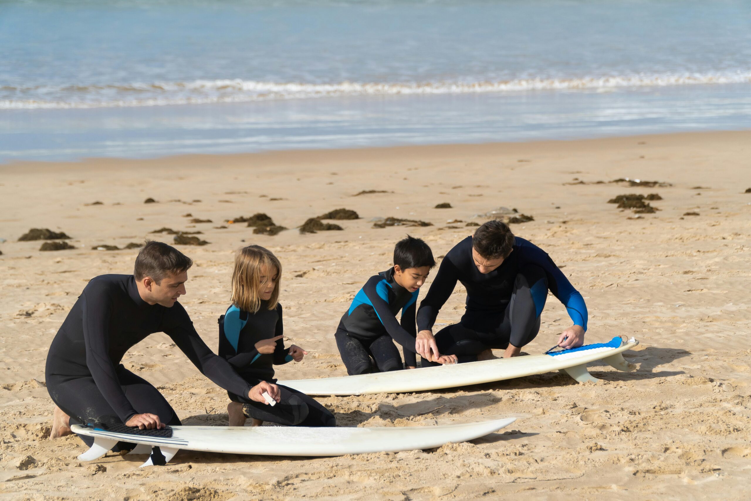 A family enjoys a surfing lesson on a sunny beach in Portugal, learning and bonding together.